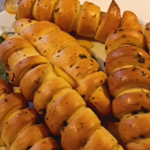 Golden-brown cheesy crescent rolls with a glossy buttery finish, arranged on a plate. The warm lighting enhances their inviting, fluffy texture.