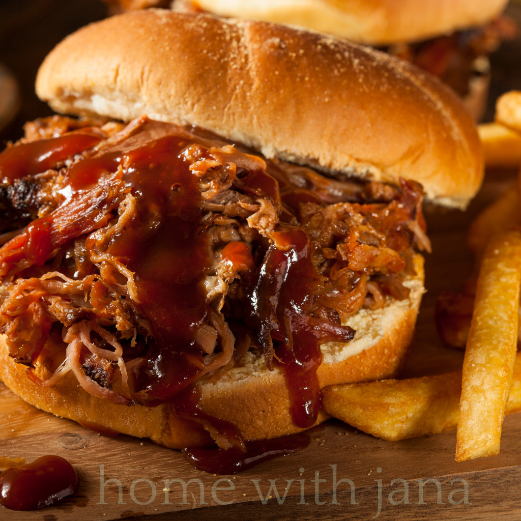 Tender, shredded slow-cooked pulled pork coated in a rich BBQ sauce, served on a rustic wooden platter with toasted brioche buns