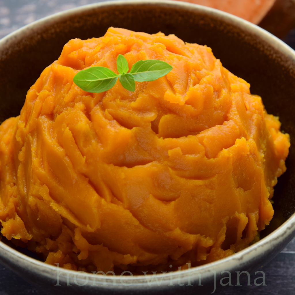 Bowl of creamy mashed sweet potatoes garnished with fresh herbs