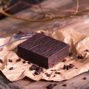 Classic Fudgy Brownie Bars cut into a neat rectangle, set on parchment with scattered chocolate chunks