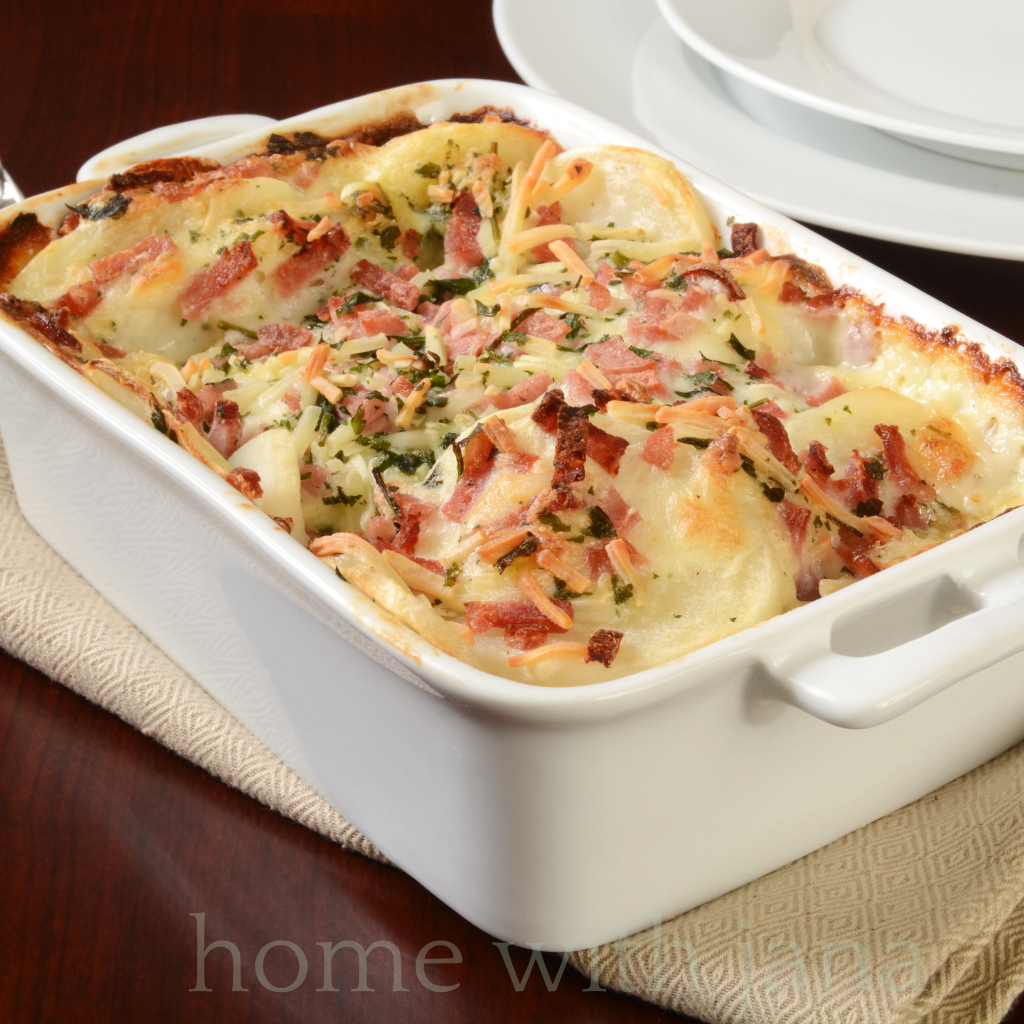 Baking dish of cheesy potato gratin with bacon and herbs