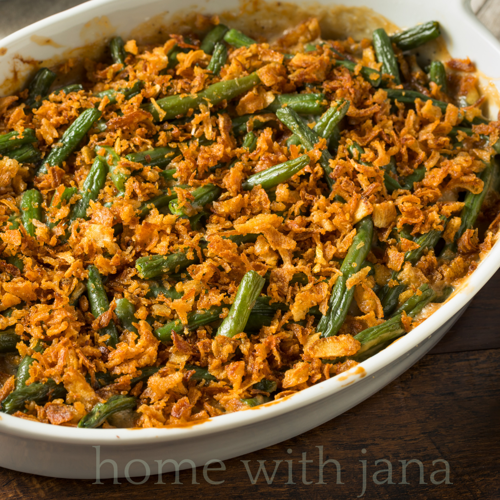 Classic green bean casserole topped with crispy fried onions in a white baking dish