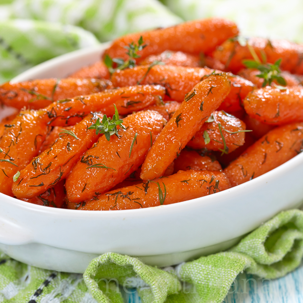 Dish of glazed carrots with butter, honey, and fresh herbs in a white casserole dish