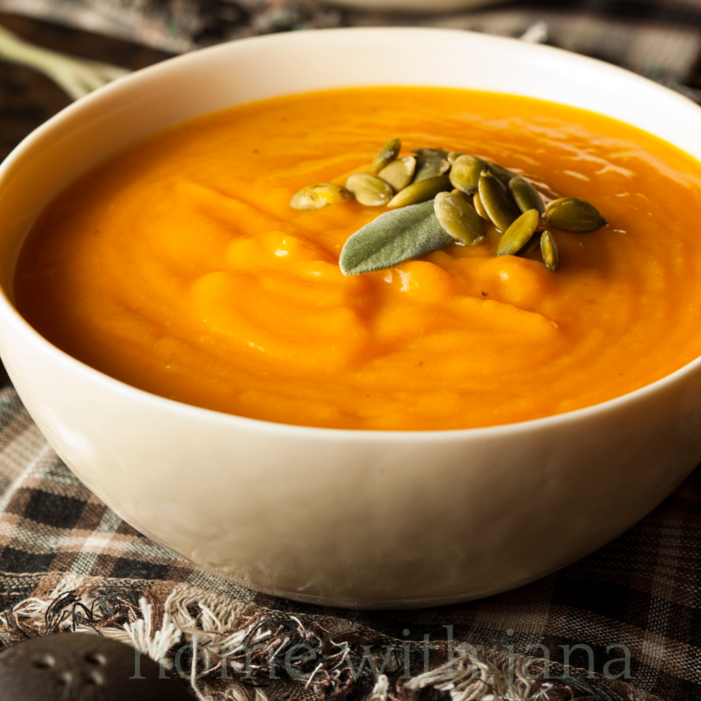 Bowl of creamy mashed butternut squash topped with sage and pumpkin seeds