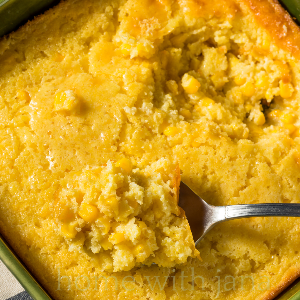 Spoon scooping creamy corn casserole from a baking dish