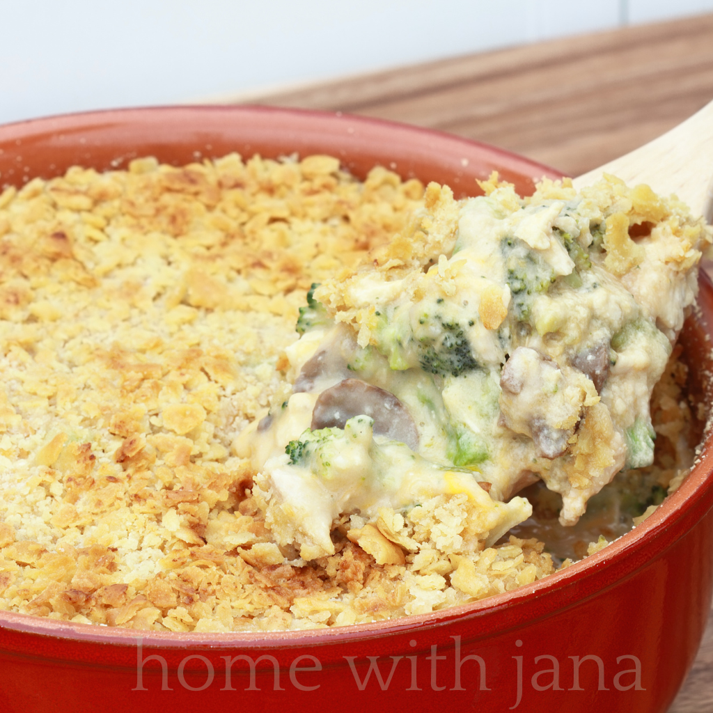 Homemade broccoli casserole with creamy cheese sauce and buttery cracker topping in a red baking dish