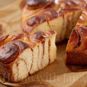 Cinnamon Roll Cake sliced sitting on parchment paper.