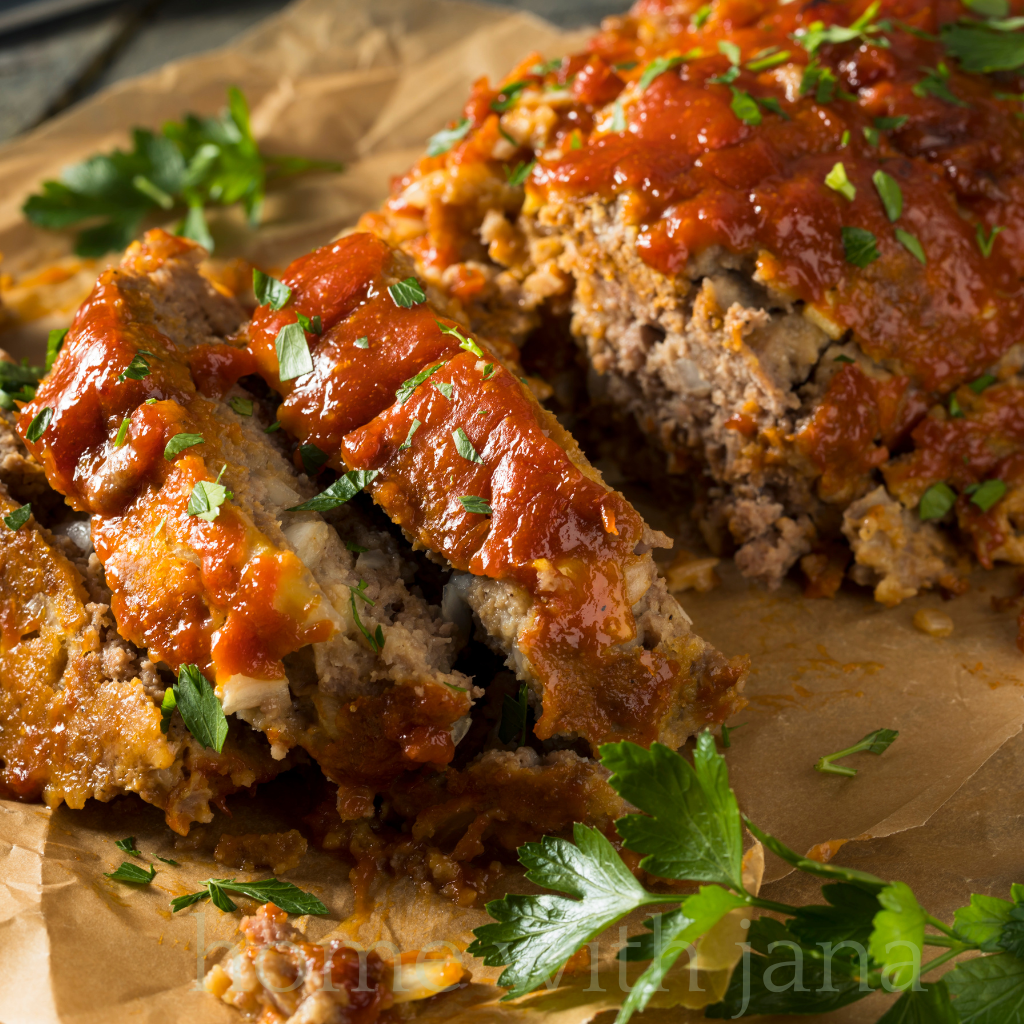 Sliced homemade meatloaf topped with tangy ketchup glaze and fresh parsley