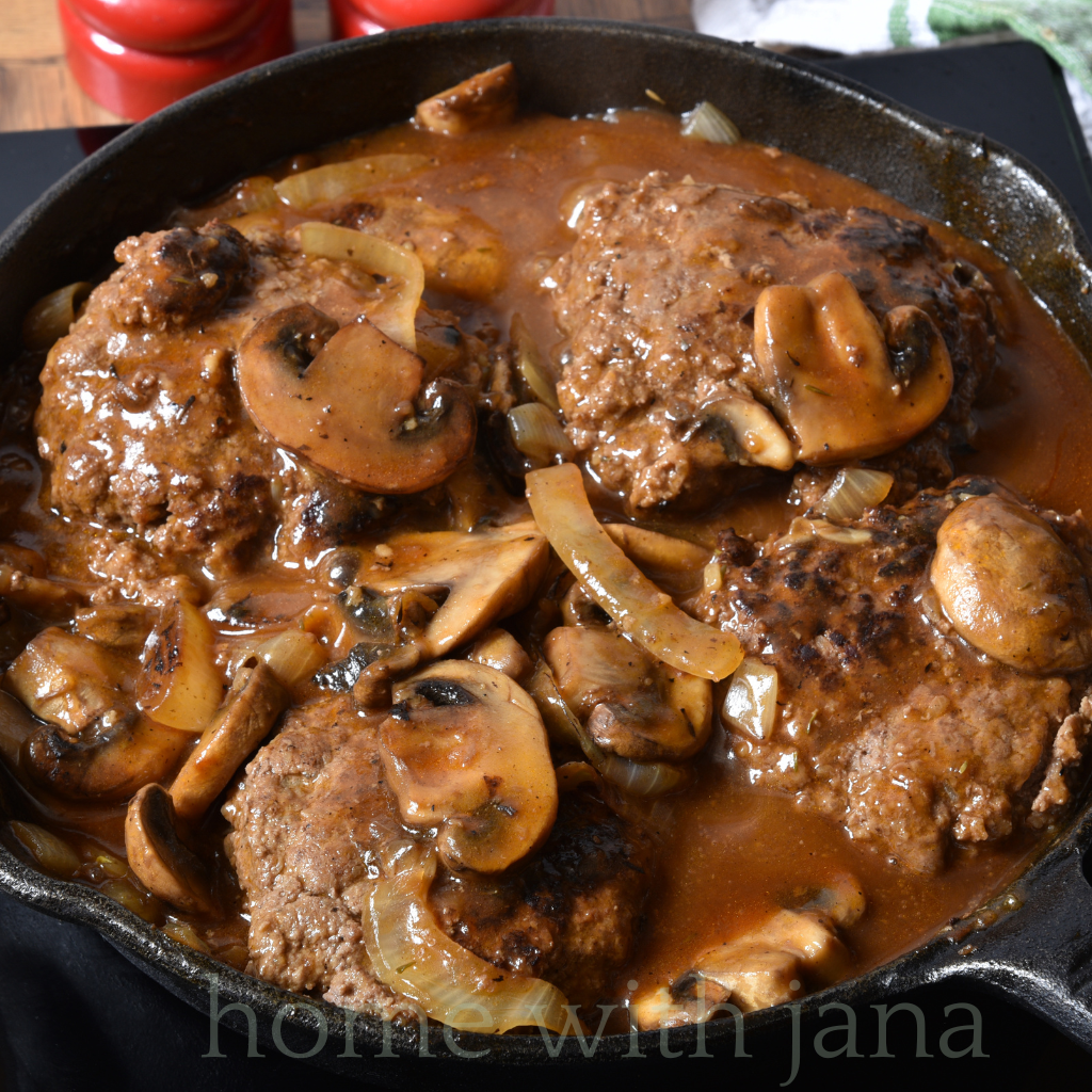 Skillet of Salisbury steak patties simmered in rich mushroom and onion gravy