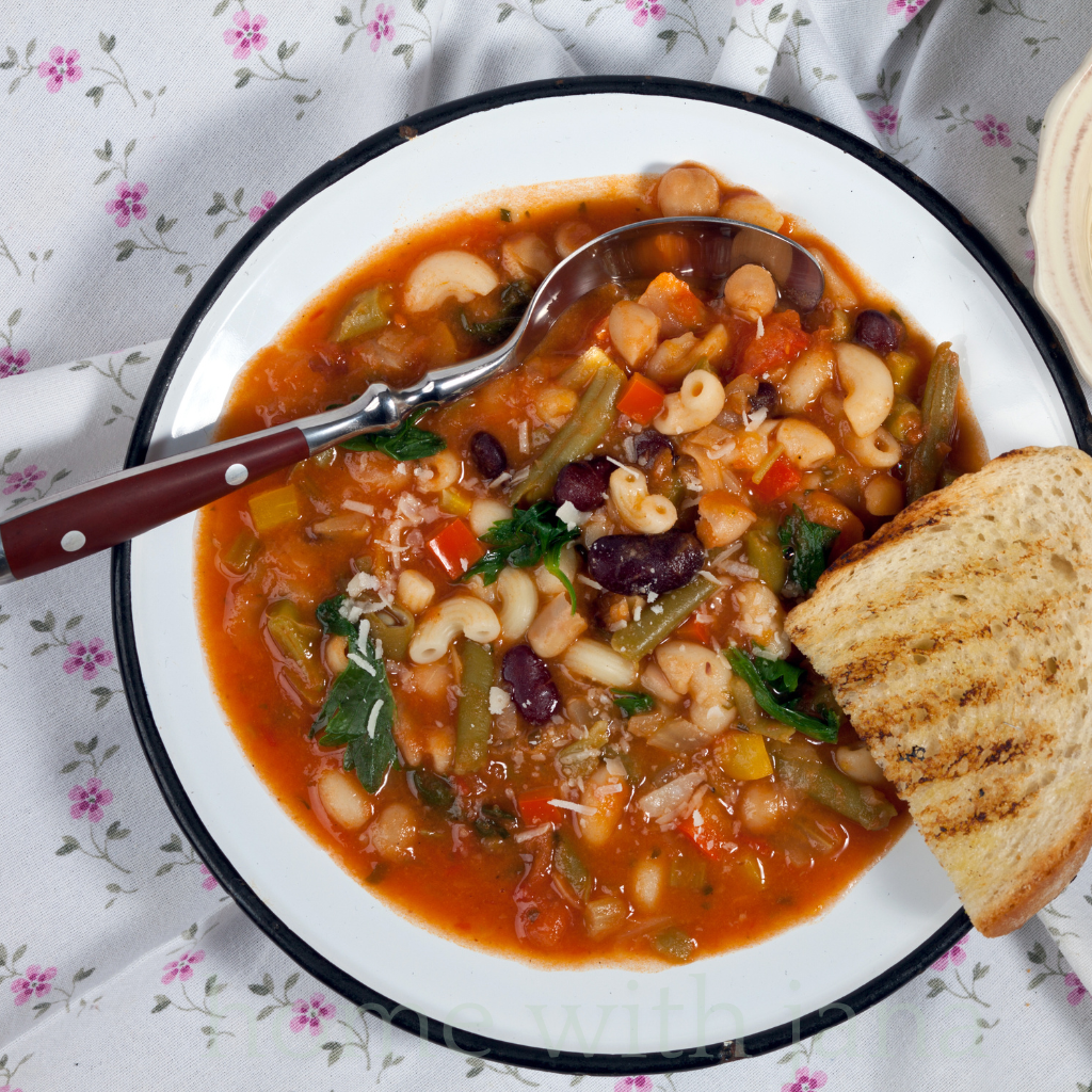 Bowl of homemade minestrone soup with beans, pasta, and vegetables served with toasted bread