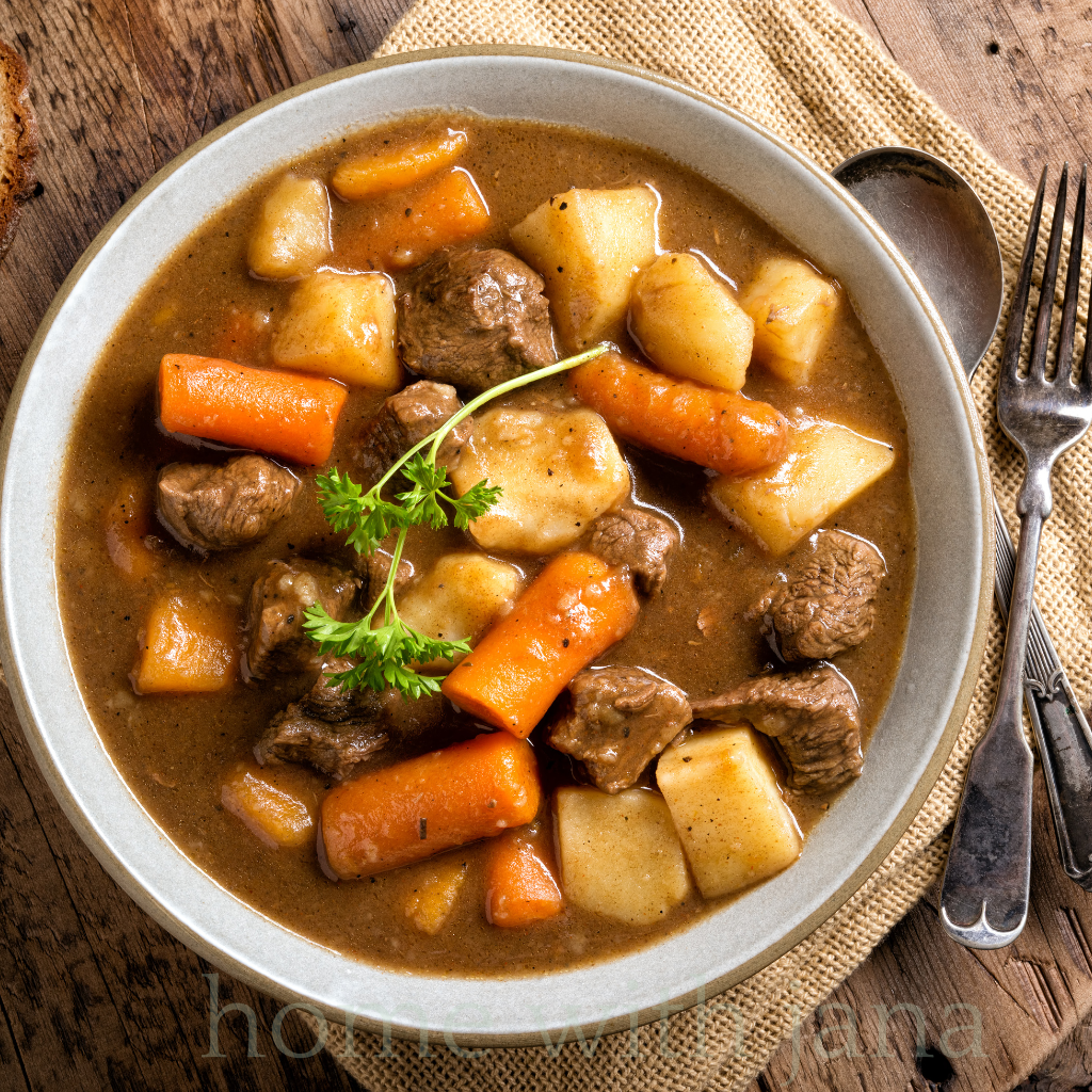 A bowl of Hearty Beef Stew in a white soup bowl sitting on a cream colored napkin.