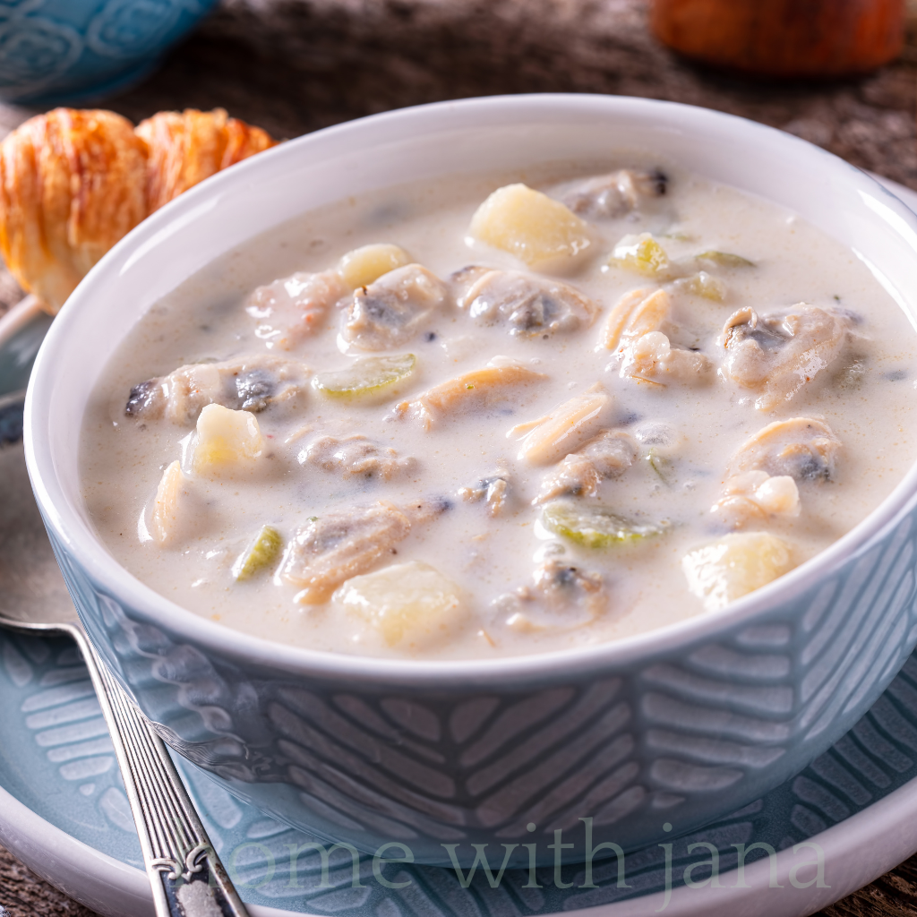 Bowl of creamy New England clam chowder with potatoes, celery, and clams in a white broth
