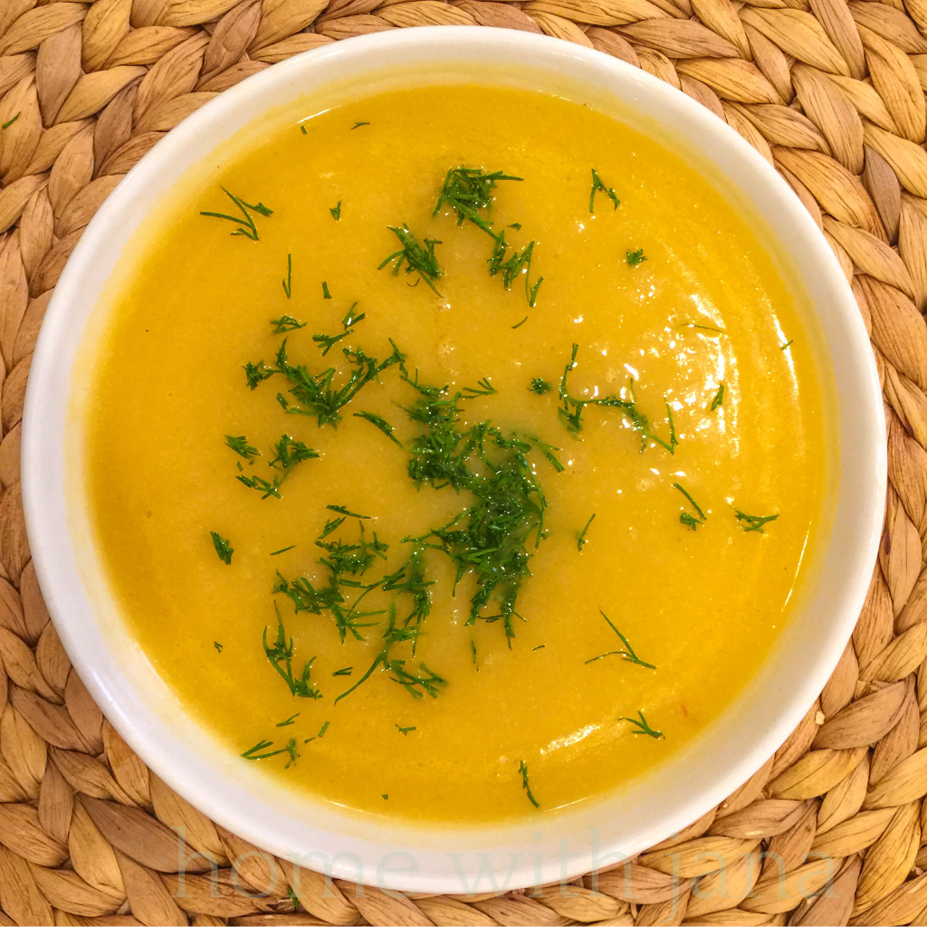 Bowl of creamy homemade pumpkin soup garnished with fresh herbs