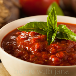 Homemade marinara sauce in a white bowl topped with fresh basil, rich tomato sauce perfect for pasta, pizza, or dipping.