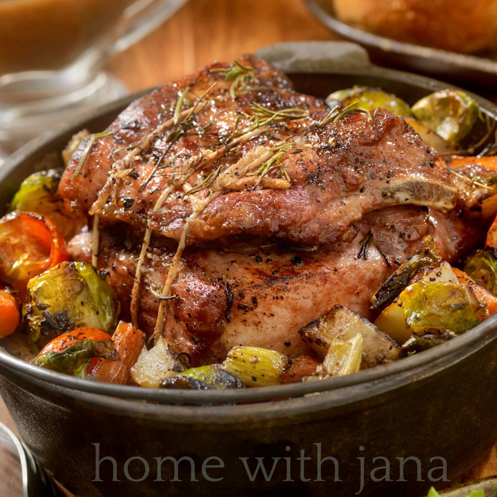 Classic beef pot roast with carrots, potatoes, Brussels sprouts, and fresh rosemary served in a cast iron pot.