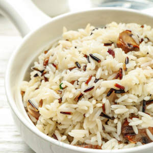 Wild rice pilaf with mushrooms and herbs served in a white bowl as a holiday side dish.
