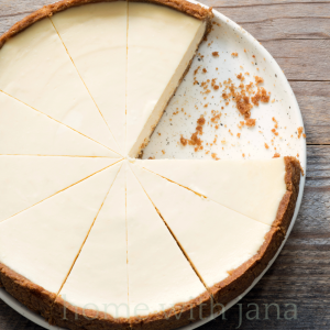 Sliced no-bake cheesecake with a graham cracker crust on a white plate, creamy and smooth dessert ready to serve.