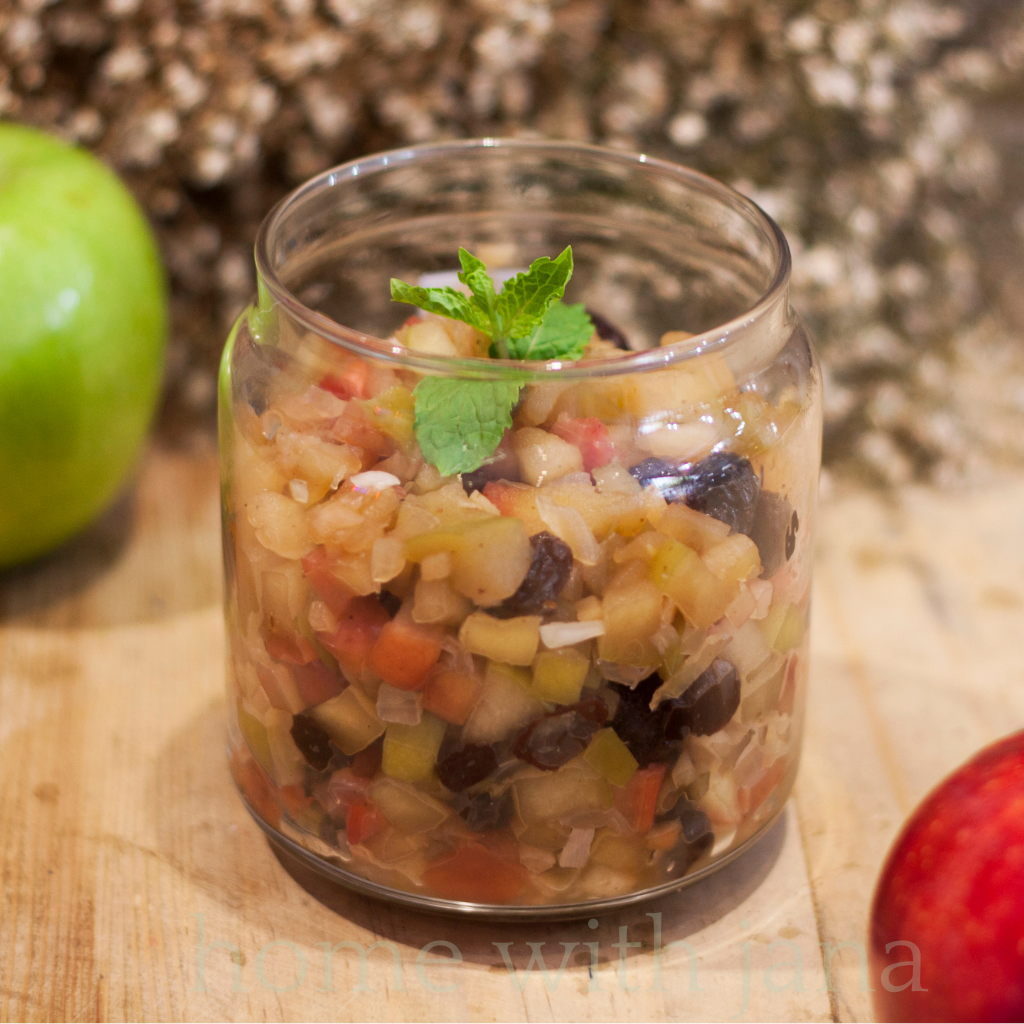 Homemade Sweet Apple Relish with raisins and diced apples in a glass jar, perfect for canning and serving with meats, sandwiches, or cheese boards.