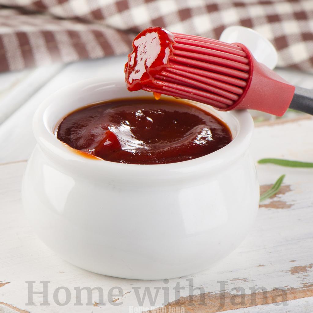Homemade barbecue sauce in a white bowl with a basting brush dipped into the sauce
