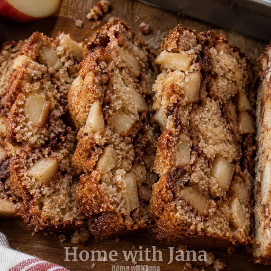 Sliced homemade apple cinnamon bread with tender apple chunks, cinnamon sugar swirls, and a golden brown crust on a rustic wooden board.
